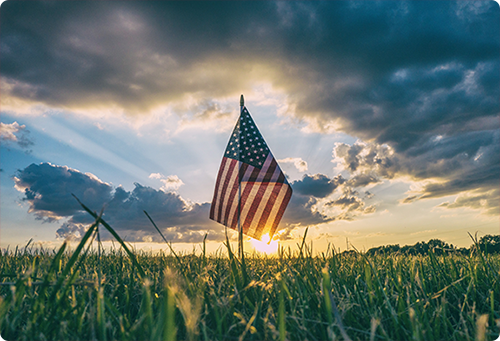 American flag waving in a grass field