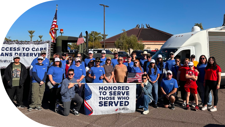 TriWest volunteers behind parade banner reading Honored to Serve Those Who Served